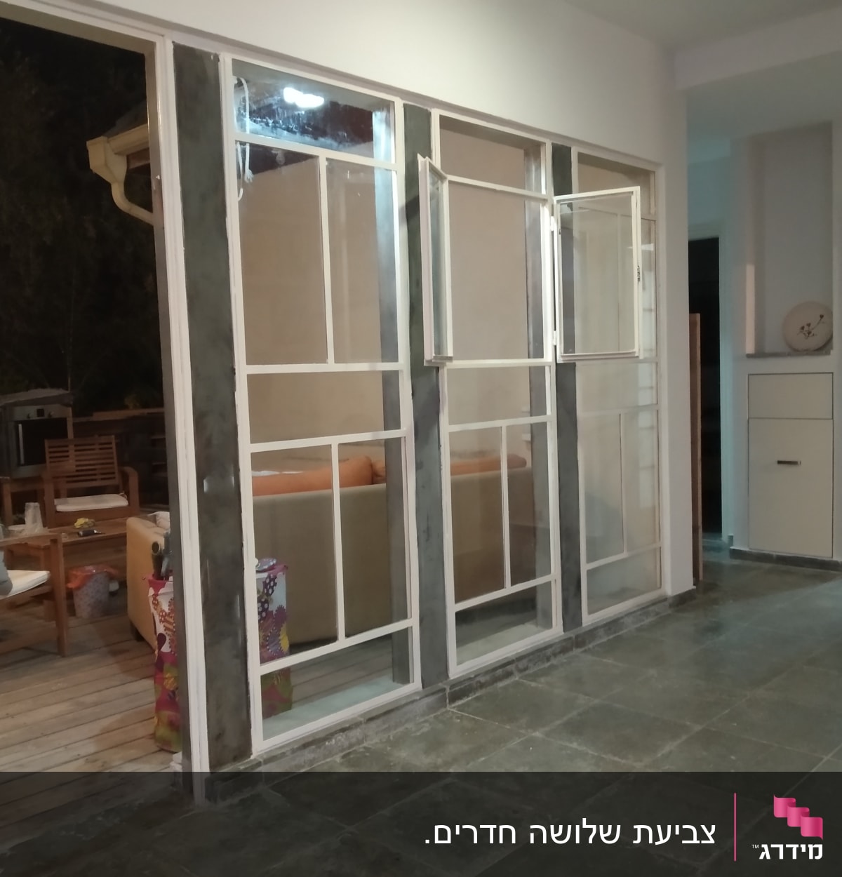 קיר עם חלונות במסגרת לבנה בתהליך צביעה